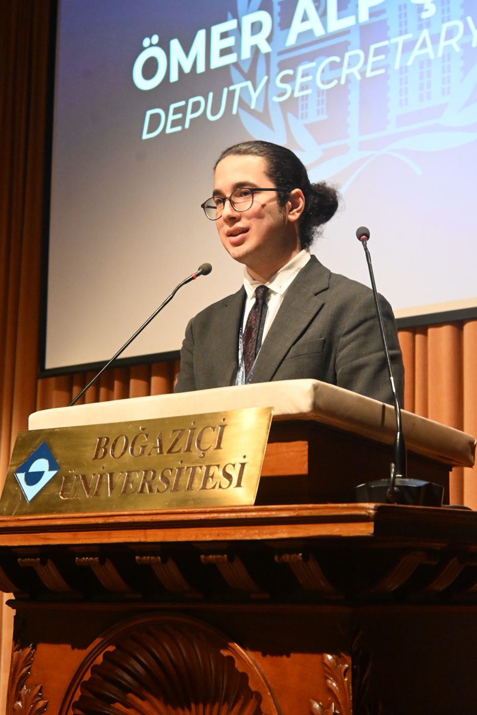 Ömer Alp Şiringöz speaking at the Albert Long Hall podium